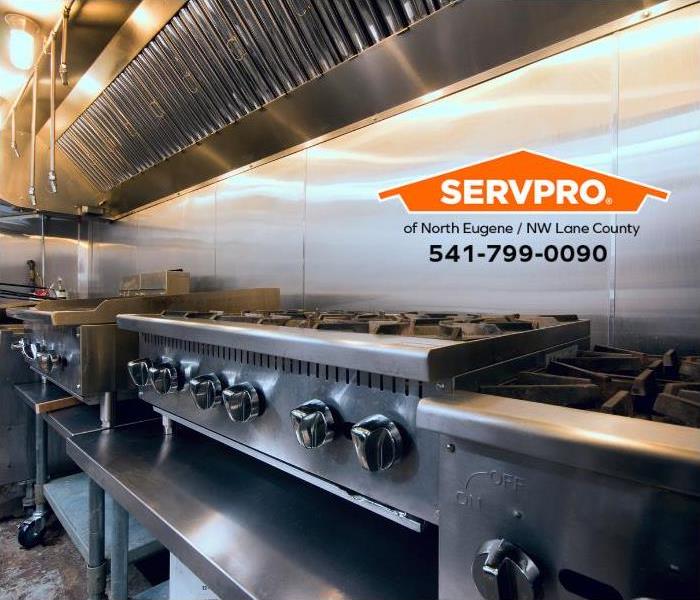 A sparkling clean commercial kitchen stove and exhaust hood are shown.