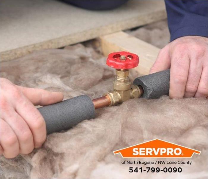 A person places insulation around water pipes to prevent them from freezing. 