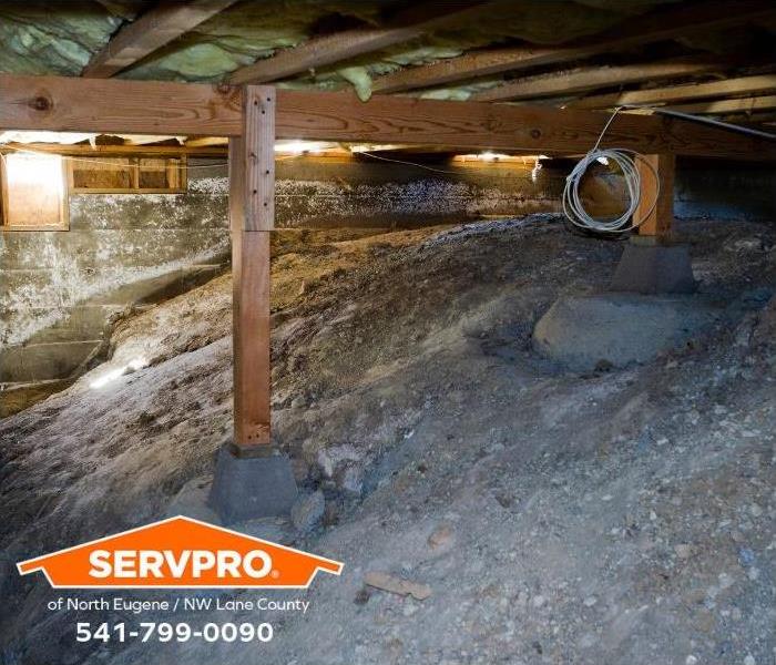 A crawl space shows visible signs of water damage in the cement block wall.